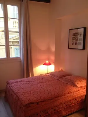 a bedroom with a bed with a lamp and a window at Appartement Les Plages in Nice