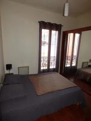 a bedroom with a bed and two large windows at Appartement Buenos Aires in Nice