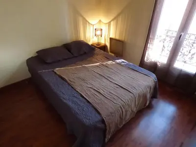 a bedroom with a bed with a blue blanket and two windows at Appartement Buenos Aires in Nice