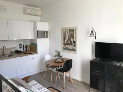a living room with a table and a kitchen at Villa le Nid in Nice