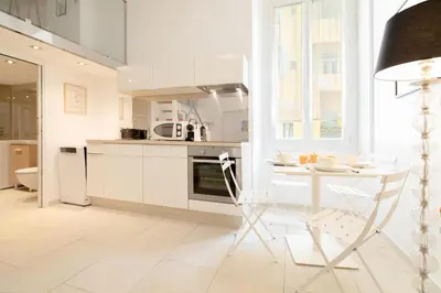 a white kitchen with a table and a chair at Maison Bianchi - Duplex old town in Nice