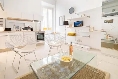 a white kitchen with a glass table and chairs at Maison Bianchi - Duplex old town in Nice