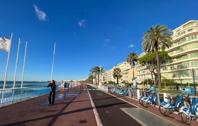 a person standing on a boardwalk next to the beach at NICE 115 BY THE SEA in Nice