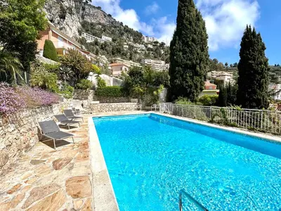 a swimming pool with two chairs and a house at Le Panomagique in Villefranche-sur-Mer