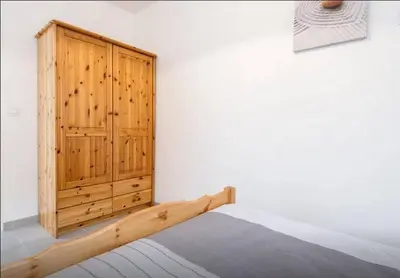 a bedroom with a bed and a wooden cabinet at La petite maison in La Gaude
