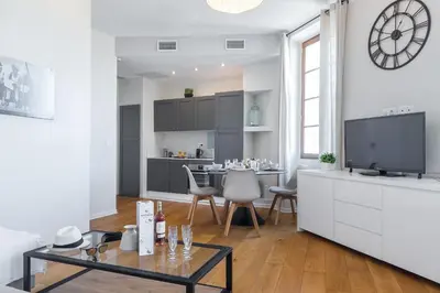 a white living room with a tv and a table at Gorgeous 1 Bdr with gardens view in the Old Town in Nice