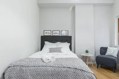a bedroom with a large bed and a blue chair at Gorgeous 1 Bdr with gardens view in the Old Town in Nice