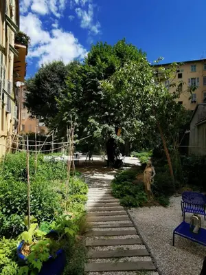 a dog sitting in a garden with a stone path at L'Abeille - Boutique Apartments in Nice