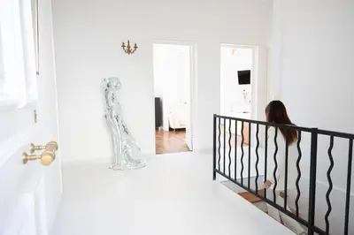 a woman walking down a staircase in a white room at Villa Belvedere in Nice