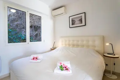 a bedroom with a white bed with two pink flowers at HENRIETTA AP4070 - avenue Soleil d'Or - Villefranche-sur-Mer in Villefranche-sur-Mer
