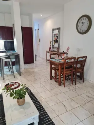 a living room with a table and chairs and a clock at la palais osiris Nice centre jardin wifi clim parking in Nice