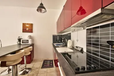 a kitchen with red cabinets and a counter with a sink at la palais osiris Nice centre jardin wifi clim parking in Nice