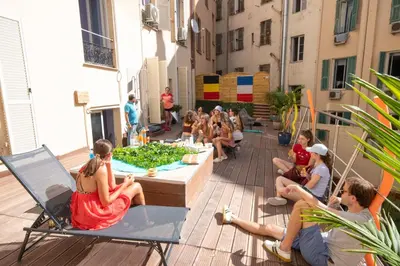 a group of people sitting around a table on a patio at Antares hostel in Nice