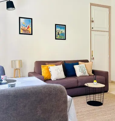 a living room with a brown couch with colorful pillows at Charmant Studio en bord de Mer in Nice