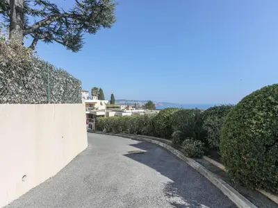 a road with a fence and bushes on the side at Apartment Domaine du Clairfontaine by Interhome in Nice