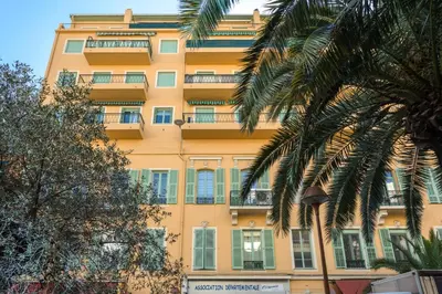 a tall yellow building with windows and palm trees at Chic appartement Centre NICE au calme vue colline in Nice