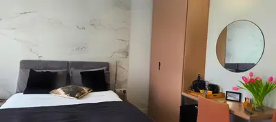 a bedroom with a bed and a desk and a mirror at Le Petit Trianon et le Charme des Suites in Nice