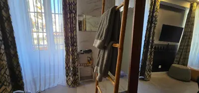 a room with a bathroom with a television and a window at Le Petit Trianon et le Charme des Suites in Nice