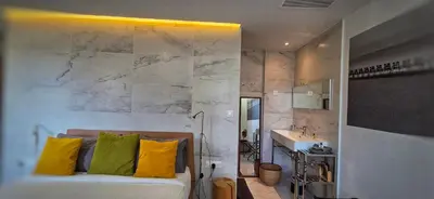 a bathroom with a bed with yellow pillows and a sink at Le Petit Trianon et le Charme des Suites in Nice