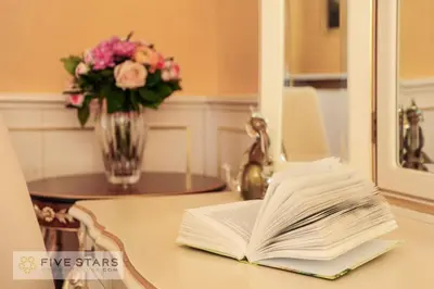 an open book on a table with a vase of flowers at Le Majestic Promenade - Five Stars Holiday House in Nice