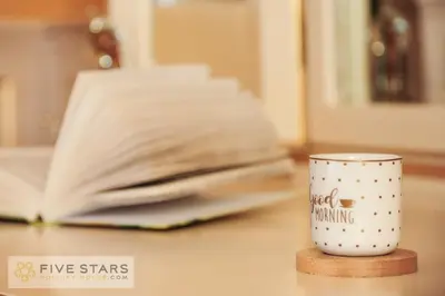 a coffee cup sitting on a table next to a book at Le Majestic Promenade - Five Stars Holiday House in Nice