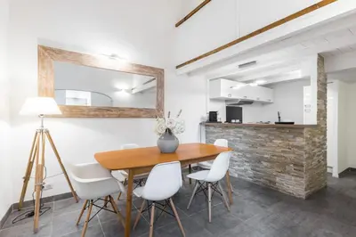 a dining room with a wooden table and white chairs at Duplex in Rue de la Préfecture Old Town 2 Bdrs in Nice