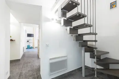 a spiral staircase in a living room with white walls at Duplex in Rue de la Préfecture Old Town 2 Bdrs in Nice