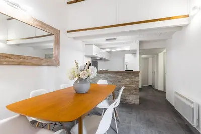 a dining room with a wooden table and white chairs at Duplex in Rue de la Préfecture Old Town 2 Bdrs in Nice