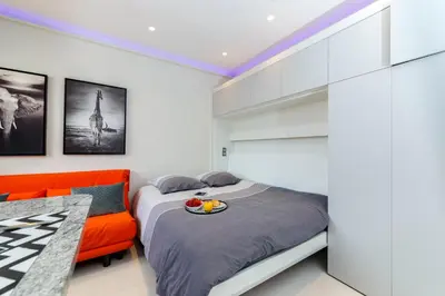 a bedroom with a bed and a orange couch at Nice Jean Médecin in Nice