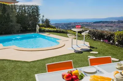 a table with a bowl of fruit sitting on the grass by a pool at LA CASETTA DEI FIORI VI3078 in Nice