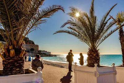 a group of people standing on a beach with palm trees at Palais Massena - Easy Home Booking in Nice