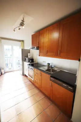 a kitchen with wooden cabinets and a counter top at Domes Seaside Résidence Piscine, Free Parking, Airport Tramway in Nice
