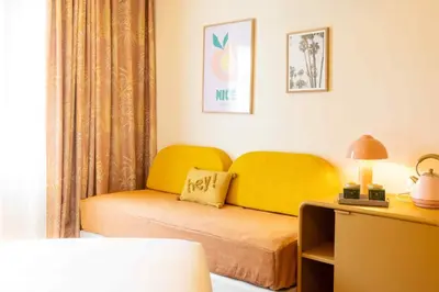 a bedroom with a bed and a yellow couch at Nice Pam Hotel in Nice