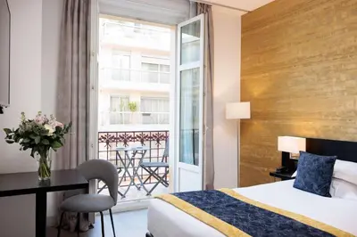 a hotel room with a bed and a desk and a balcony at Best Western Plus Hôtel Massena Nice in Nice
