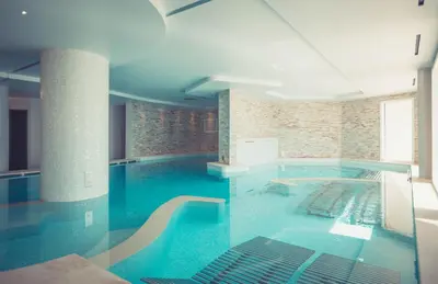 a large swimming pool with blue water in a building at Les Terrasses d'Eze - Hôtel & Spa in Èze
