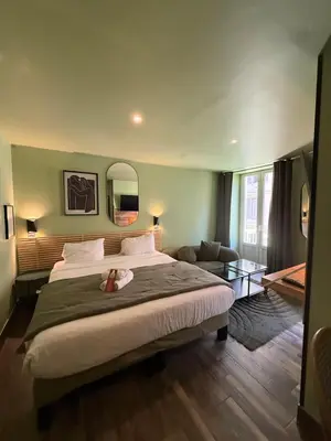 a bedroom with a large bed and a glass table at Hotel de Berne in Nice