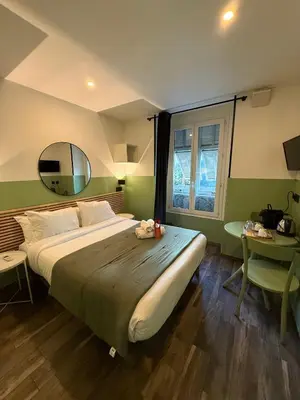 a bedroom with a bed and a table and a mirror at Hotel de Berne in Nice