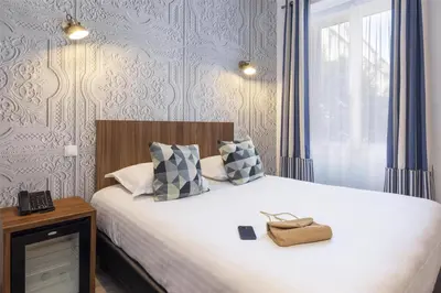 a bedroom with a white bed with a window and a phone at Best Western Plus Hôtel Brice Garden Nice in Nice