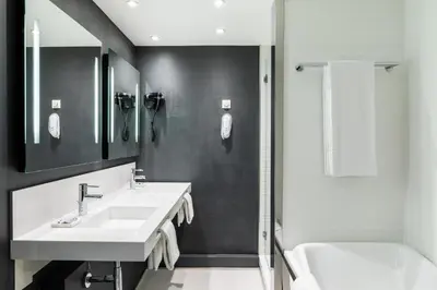 a white bathroom with two sinks and a bath tub at AC Hotel by Marriott Nice in Nice
