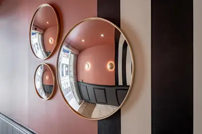 a mirror on a wall with three mirrors on it at Hôtel Le Seize, Nice Centre in Nice