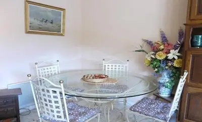 a glass table with four chairs and a vase of flowers at AZURELLE in Nice