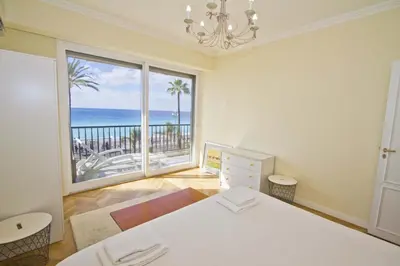 a bedroom with a bed and a large window with the ocean at PROMENADE HOLIDAY - CARIATIDE PROMENADE SEA VIEW in Nice