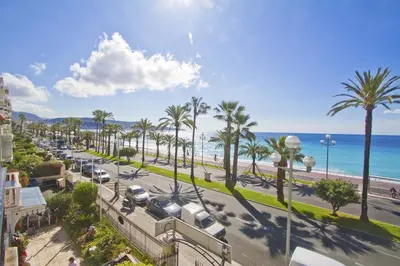 a view of a street with palm trees and the ocean at PROMENADE HOLIDAY - CARIATIDE PROMENADE SEA VIEW in Nice