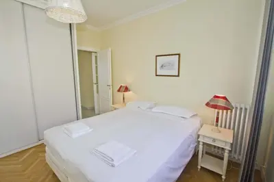 a bedroom with a white bed and a table with a lamp at PROMENADE HOLIDAY - CARIATIDE PROMENADE SEA VIEW in Nice