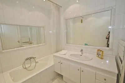 a white bathroom with a sink and a tub and a mirror at PROMENADE HOLIDAY - CARIATIDE PROMENADE SEA VIEW in Nice