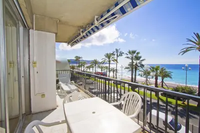 a balcony with a table and chairs and a view of the beach at PROMENADE HOLIDAY - CARIATIDE PROMENADE SEA VIEW in Nice