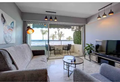 a living room with a couch and a tv and a table at Flat design with SEA view promenade des anglais in Nice