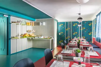 a dining room with tables and chairs and colorful walls at Hôtel les Cigales in Nice