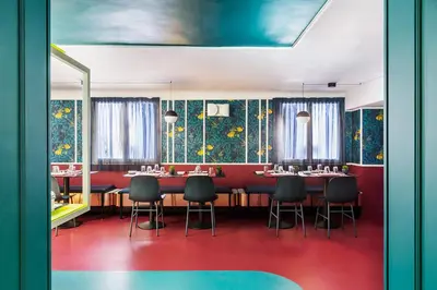 a dining room with tables and chairs and a wall with flowers at Hôtel les Cigales in Nice