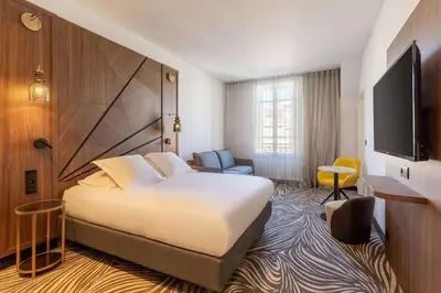 a hotel room with a bed and a flat screen tv at Hôtel Apollinaire Nice in Nice